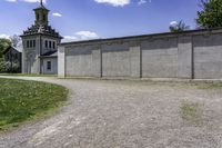 an empty concrete building near a grassy field in front of a large church tower and clock tower