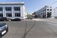 a car sits parked at an intersection with buildings in the background and cars are visible