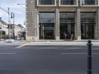 an empty street next to a building with many windows and lamps and a large sign that reads no parking