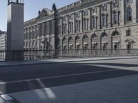 a clock tower near some buildings on a sunny day, behind a railing that says town hall