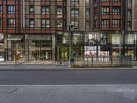 a busy city street with a bicycle and people passing by in a line of stores