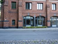 a street in front of a red brick building with a window in the middle of it