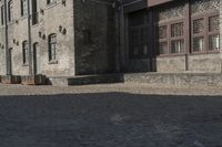 the person is walking down the street near old buildings on a sunny day with a red umbrella