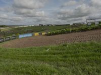 this is an image of a tractor plowing a field at a farm near houses