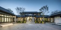 the entrance of this traditional asian - style home is lit up in white lights and green plants