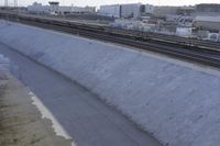 a view of a long wall that has a train going down it and buildings in the background