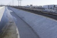 a view of a long wall that has a train going down it and buildings in the background