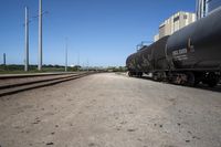 a train engine with its tank cars pulled along tracks in a rural setting near other railroad tracks