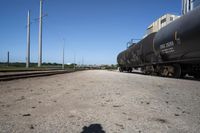 a train engine with its tank cars pulled along tracks in a rural setting near other railroad tracks