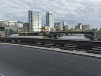 this is the train going over the bridge near the cityscape and river with some buildings