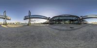 a wide angle view of the sun in front of a train station building while it's going down