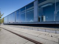 a train tracks that are next to a glass wall in a building with a city skyline in the background