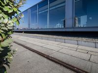 a train tracks that are next to a glass wall in a building with a city skyline in the background