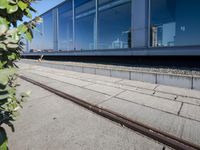 a train tracks that are next to a glass wall in a building with a city skyline in the background