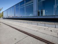 a train tracks that are next to a glass wall in a building with a city skyline in the background