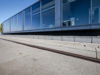 a train tracks that are next to a glass wall in a building with a city skyline in the background