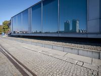 a train tracks that are next to a glass wall in a building with a city skyline in the background