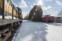 a train traveling down tracks with snow and trees behind it as the sun shines brightly on the left side