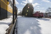 a train traveling down tracks with snow and trees behind it as the sun shines brightly on the left side