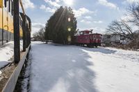 a train traveling down tracks with snow and trees behind it as the sun shines brightly on the left side