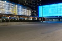 a street with a large light blue screen on the side of it next to a building