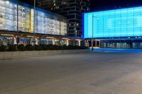 a street with a large light blue screen on the side of it next to a building