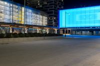 a street with a large light blue screen on the side of it next to a building