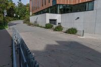 the sidewalk along this side of a building in a city with concrete walls and columns