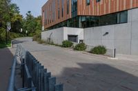 the sidewalk along this side of a building in a city with concrete walls and columns