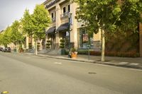 a car is on the side walk by a tree lined street with buildings and shops in front
