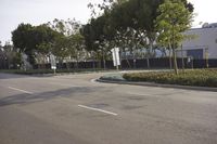 a street is lined with trees in front of a warehouse building that's opposite side