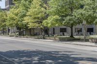 a city street filled with lots of trees and shrubs near a sidewalk lined with benches