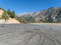 a paved parking lot in a wooded area, with a blue sky and mountain in the background