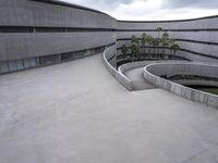 a building with cement roof near green grass and lawn in front of it, under a gray sky