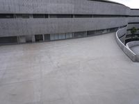 a building with cement roof near green grass and lawn in front of it, under a gray sky