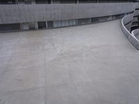 a building with cement roof near green grass and lawn in front of it, under a gray sky