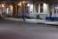 people are walking on a sidewalk at night in the city alone and in the city at night