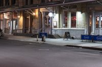 people are walking on a sidewalk at night in the city alone and in the city at night