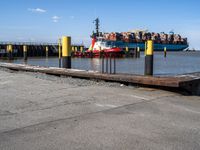 a truck and some cars are sitting on a dock next to a pier, and a yellow guard line with a big truck on it