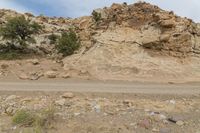 a truck drives through a desert area near the cliff face with a small rock formation