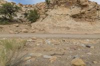 a truck drives through a desert area near the cliff face with a small rock formation