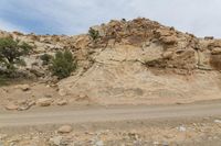 a truck drives through a desert area near the cliff face with a small rock formation