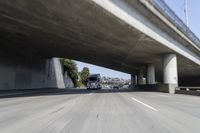 a truck is driving along the highway under a bridge and road crossing over it,