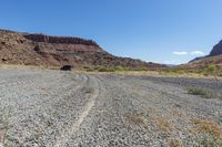 a truck is on the dirt in the open field of some sort, with large rocks behind it