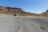 a truck is on the dirt in the open field of some sort, with large rocks behind it