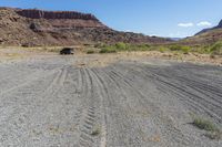 a truck is on the dirt in the open field of some sort, with large rocks behind it