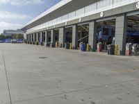 a truck repair shop with yellow line paint and some trash cans and containers in front