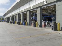 a truck repair shop with yellow line paint and some trash cans and containers in front