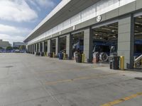 a truck repair shop with yellow line paint and some trash cans and containers in front