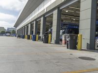 a truck repair shop with yellow line paint and some trash cans and containers in front